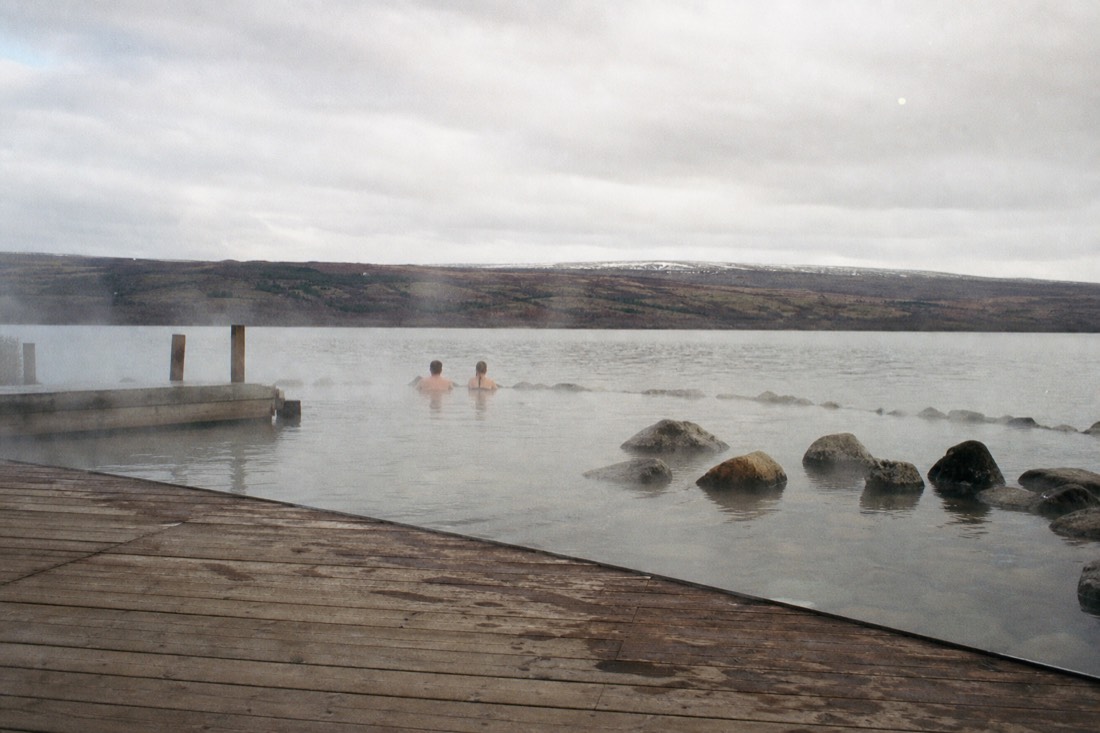 Steam rising off the shallow warm bathing pools at Laugarvatn Fontana beside the lake in overcast light