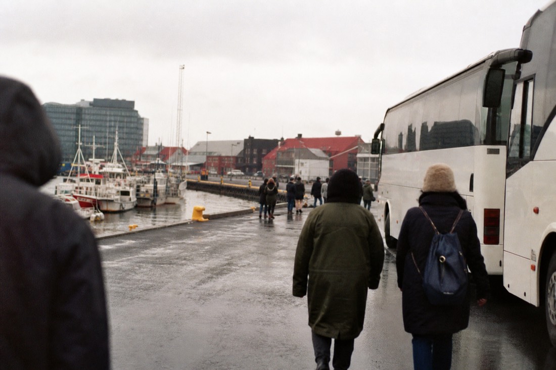 Tour buses and fishing boats along the old harbour in Reykjavík in light drizzle