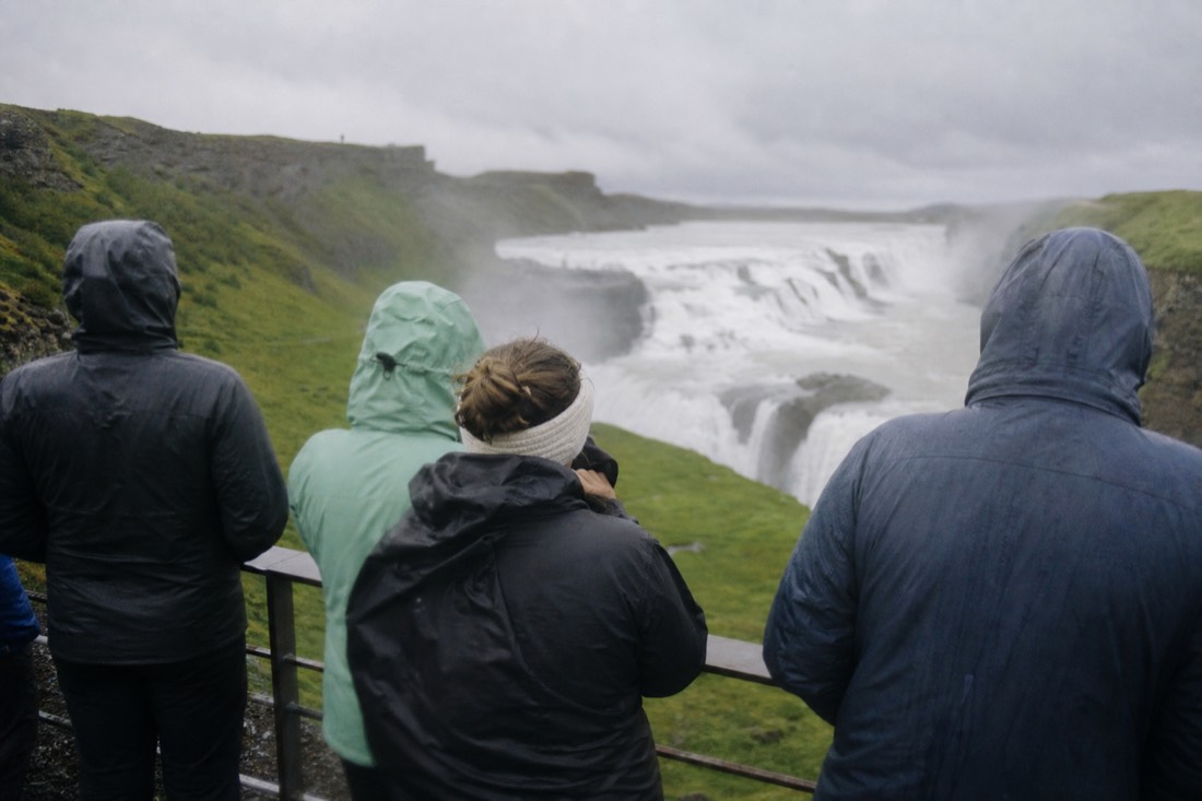 A small tour group seen from behind on the upper viewing platform above Gullfoss waterfall