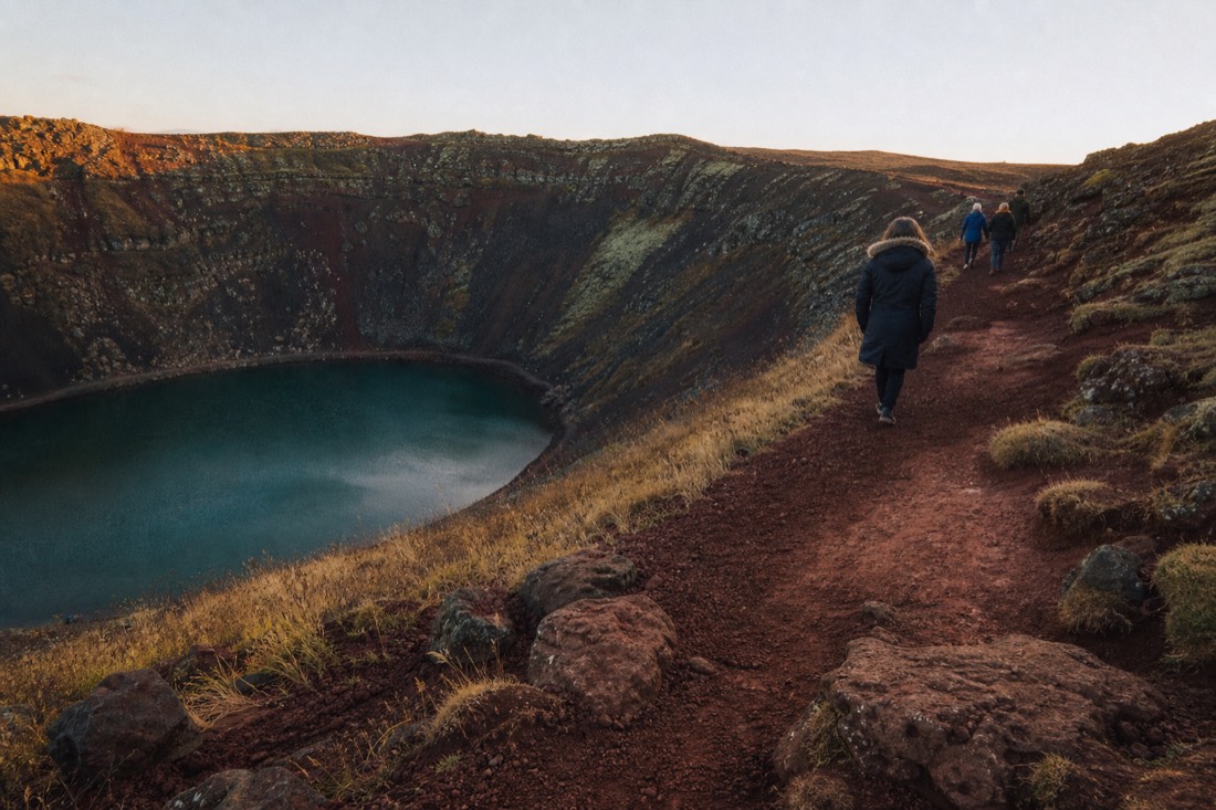 The red scoria rim path around the Kerið crater lake in low golden evening light