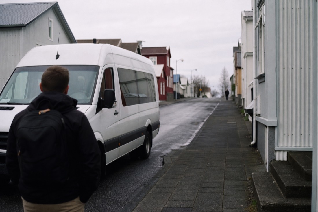 Unbranded white minibus waiting on a quiet Reykjavík street at morning pickup time