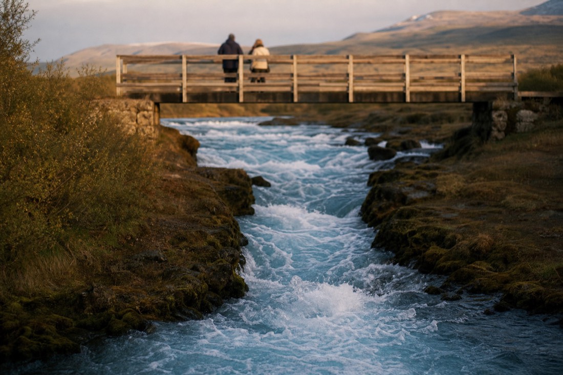 Milky blue water of Brúarfoss churning below the footbridge over the Brúará river in evening light